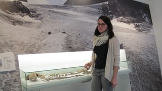 Projektleiterin Leandra Reitmeier vor einer Glasvitrine mit Funden aus dem Gletscher.