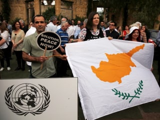 Ein Mann und eine Frau demonstrieren mit einer zypriotischen Flagge für die Vereinigung.