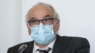 Mann mit Maske an Medienkonferenz. 