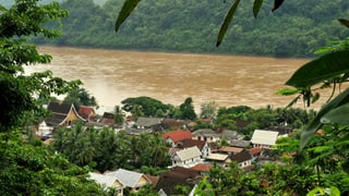 Blick auf eine Siedlung und einen Fluss in Laos.
