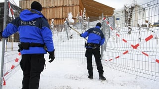 Zwei Polizisten räumen in Davos Schnee weg. Zwei Polizisten räumen in Davos Schnee weg.