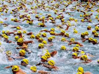 Zu sehen sind hunderte von Triathleten auf der Schwimmstrecke. 