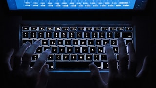 Laptop-Tastatur, auf der zwei Hände tippen.