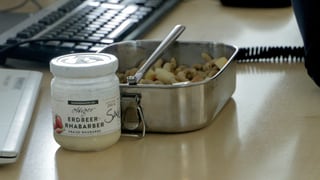 Ein Aluminium-Behälter mit Essen drin. Daneben steht ein Glas mit Salatsauce. Ein Aluminium-Behälter mit Essen drin. Daneben steht ein Glas mit Salatsauce.