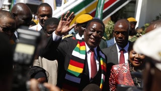 Mnangagwa zwischen anderen Menschen, er winkt in die Kamera. Mnangagwa zwischen anderen Menschen, er winkt in die Kamera.