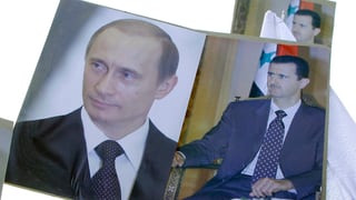 Demonstranten tragen Plakate mit den Porträts von Putin und Assad