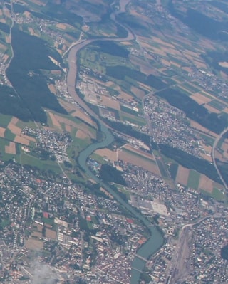 Ein Flugbild des Mittellandes mit Feldern, Wäldern und Siedlungsgebiet. Gut ist die Aare wie eine Schlange sichtbar. Erst ist die blau, mit dem Einfliessen der Emme wird sie drecki-braun. 