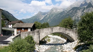 Eine Steinbrücke überquert ein steiniges Bachbett.