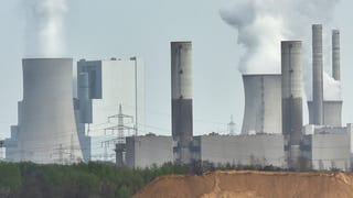 Fünf rauchende Atomkraftwerke in einer düsteren Landschaft.