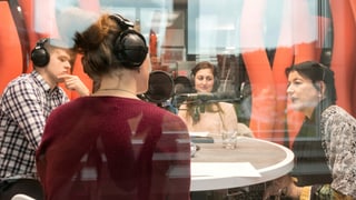 Drei Frauen und ein Mann sitzen mit Kopfhörern in einem Radiostudio und diskutieren. Drei Frauen und ein Mann sitzen mit Kopfhörern in einem Radiostudio und diskutieren.