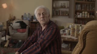 Ein Schauspieler, der Gurlitt spielt, sitzt in Pyjama in einem unaufgeräumten Wohnzimmer. Ein Schauspieler, der Gurlitt spielt, sitzt in Pyjama in einem unaufgeräumten Wohnzimmer.