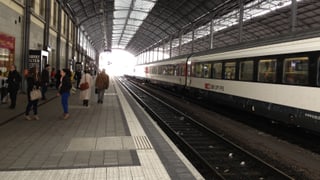 Bahnhof Olten, Blick aufs Perron, daneben steht ein Zug still. In der Ferne sieht man das Licht durch das Ende des Pavillons scheinen.