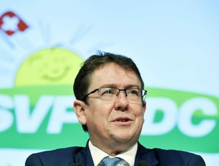 Rösti vor dem SVP-Logo.