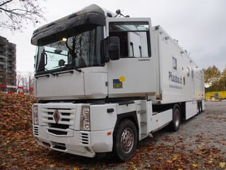 Ein grosser Lastwagen mit Anhänger steht auf einem Kiesfeld.