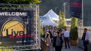 Blick auf den Festivaleingang mit vielen Leuten und einem grossen Festivalplakat. 