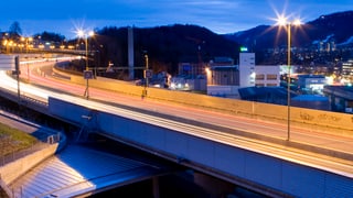 Eine Strasse in der Abenddämmerung mit vielen hellen Strassenlampen, die leuchten.