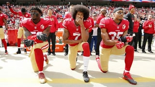 Football-Spieler Colin Kaepernick und zwei Teamkollegen knien während der Hymne.
