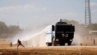 Ein Polizeifahrzeug setzt einen Wasserwerfer gegen kurdische Demonstranten ein.