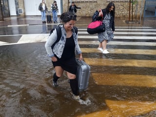 Several women walking down a flooded street.
