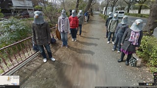 Acht Männer und Frauen mit Vogel-Masken.