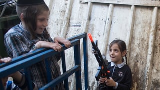 Zwei Kinder spielen, ein Mädchen hält eine Plastikwaffe in der Hand. Zwei Kinder spielen, ein Mädchen hält eine Plastikwaffe in der Hand.
