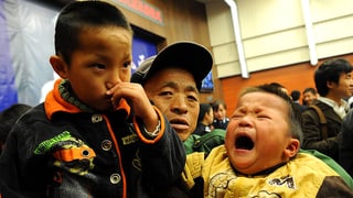 Zwei gerettetet Jungs in den Armen ihres Vaters. Der jüngere Bub weint. Foto von 2009.
