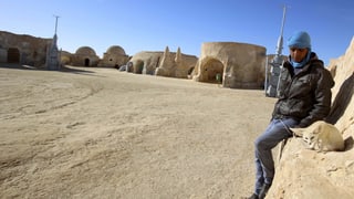 Junger Mann mit Wüsten Hund vor Steinbauten