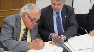 Mann unterschreibt ein Papier Mann unterschreibt ein Papier