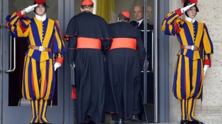 Kardinäle betreten ein Haus, das von Schweizer Gardisten bewacht wird.