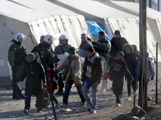 Flüchtlinge werden von Polizisten an Zelten vorbeigeleitet