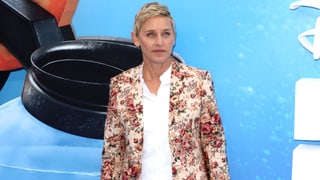 Ellen DeGeneres posiert vor einem Plakat. 