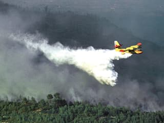 Ein Löschflugzeug versprüht Wasser über einem brennenden Wald. (Spanien) Ein Löschflugzeug versprüht Wasser über einem brennenden Wald. (Spanien)