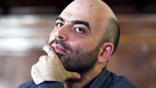 Autor Roberto Saviano stützt sein Kinn in die Hand und hat einen nachdenkliche Blick. 