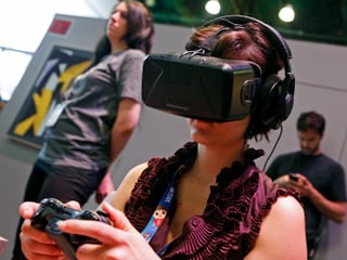 Eine Frau trägt beim Gamen eine Entwickler-Version der Oculus Rift Virtual-Reality-Brille. Eine Frau trägt beim Gamen eine Entwickler-Version der Oculus Rift Virtual-Reality-Brille.