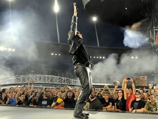 Mann auf Bühne vor Publikum streckt Arm in die Luft