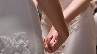 Zwei Frauen vor dem Traualtar halten sich die Hände