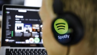 Ein junger Mann mit Spotify-Kopfhörern hört sich Musik bei Spotify an.