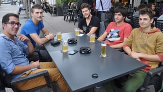 Fünf junge Männer an einem Tisch im Gartenrestaurant. Darauf stehen Gläser und Aschenbecher. 