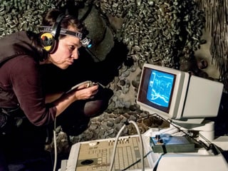 Frau steht neben einer schuppigen Fläche und untersucht diese mit einem Ultraschallgerät. Frau steht neben einer schuppigen Fläche und untersucht diese mit einem Ultraschallgerät.