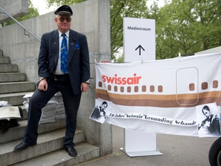 Ein Mann in Uniform steht neben einem Swissair-Banner