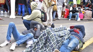 Junge Männer liegen in der Kälte auf dem Boden, zugedeckt von einer Wolldecke. Sie tragen Handschuhe.