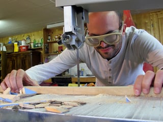 Mann mit Schutzbrille an einer Sägemaschine.
