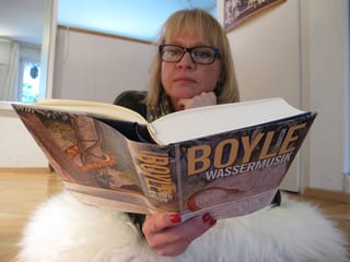 Daniela Lager liegt lesend auf einem weissen Fell am Boden. Daniela Lager liegt lesend auf einem weissen Fell am Boden.