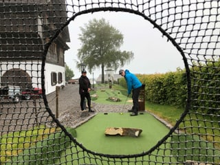 Zwei Menschen spielen einen Minigolfball durch ein Netz.