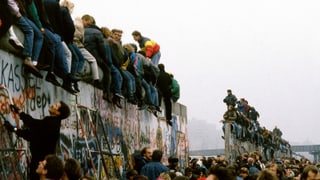 Menschen auf der Mauer sitzend.