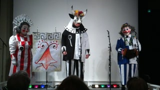Drei Personen in Schnitzelbank-Kostümen auf der Theaterbühne. 