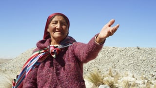 Eine peruanische Bäuerin zeigt auf die Umgebung, die von der Mine verschmutzt wird.