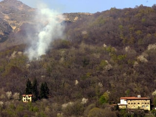 An einem Hang im Tessin steigen Rauchschwaden aus dem trockenen Bewuchs, die Aufnahme stammt von Ostern 2001.