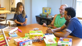Zwei Männer und ein Kind spielen Uno.