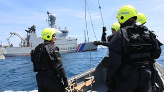 Isländische Frontex-Einsatzkräfte mit gelben Helmen auf einem Boot.